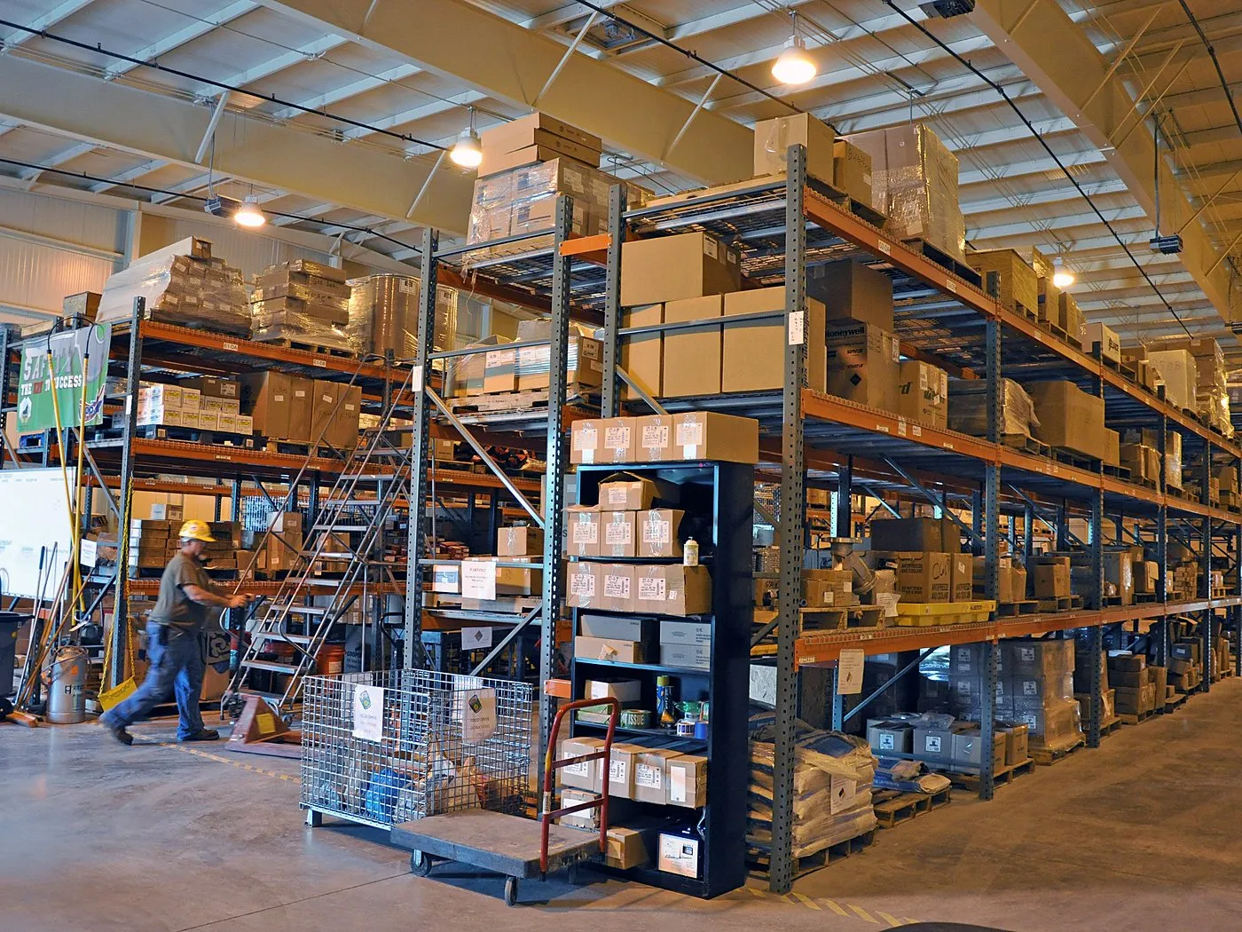 Depósito con estanterías de cajas y un operario preparando pedidos